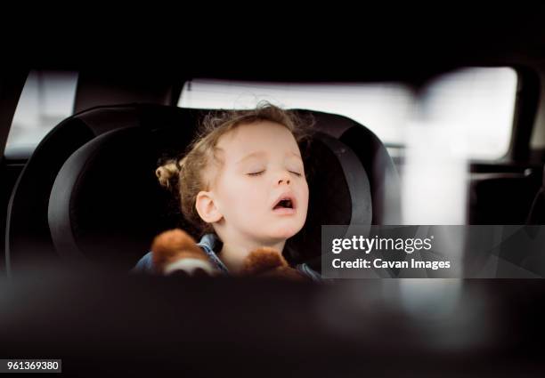 cute girl with mouth open sleeping in car seen through vehicle seat - sleeping in car stockfoto's en -beelden