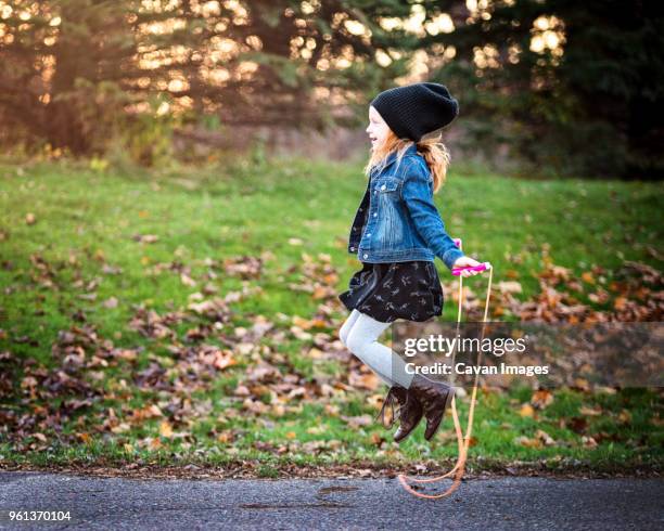 side view of girl jumping rope on footpath at park during autumn - dar brincos fotografías e imágenes de stock