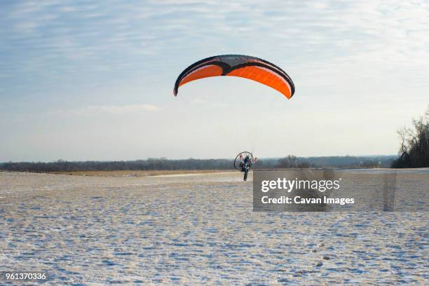 young man motor paragliding over field against sky - motor paraglider stock pictures, royalty-free photos & images