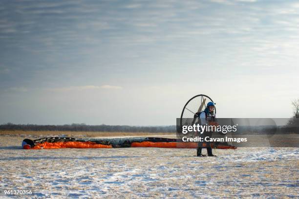 young man removing electric motor while standing on field against sky - motor paraglider stock pictures, royalty-free photos & images