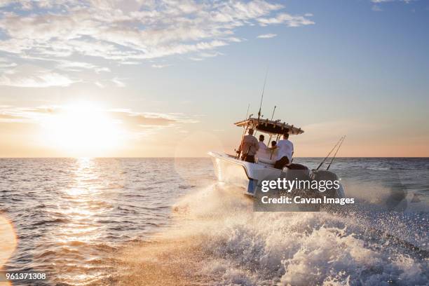 men enjoying in speedboat at sea against sky during sunset - schnellboot stock-fotos und bilder