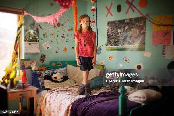 portrait of girl standing on bed in room - child's bedroom stockfoto's en -beelden