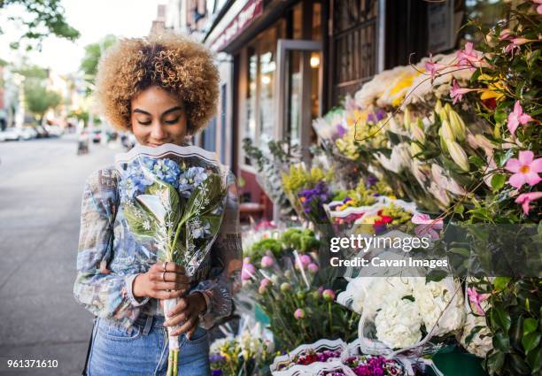 smiling woman smelling hydrangeas outside flower shop - cavan images stock-fotos und bilder