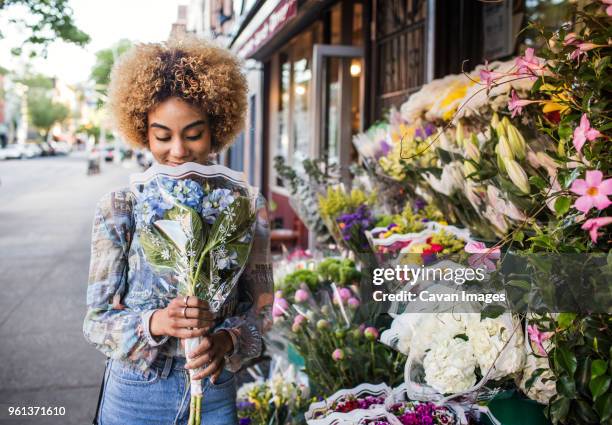 smiling woman smelling hydrangeas outside flower shop - casual clothing store stock pictures, royalty-free photos & images