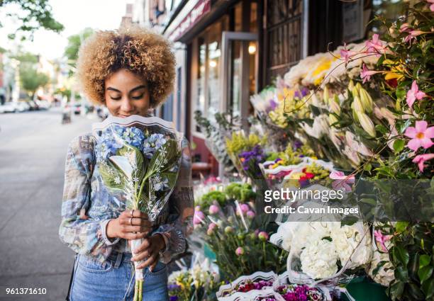 smiling woman smelling hydrangeas outside flower shop - smelling 個照片及圖片檔