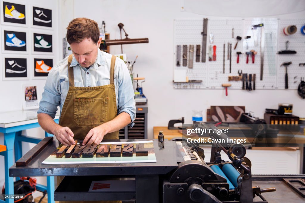 Serious man working on wooden alphabets in printing press