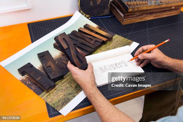 cropped image of man holding wooden alphabets and copying in paper - typesetter stock pictures, royalty-free photos & images