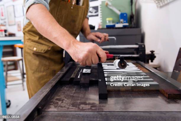 side view of man painting wooden alphabets in printing press - table font view stock pictures, royalty-free photos & images