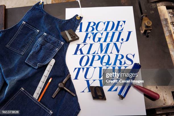 high angle view of apron by poster and tools on table - table font view stock pictures, royalty-free photos & images