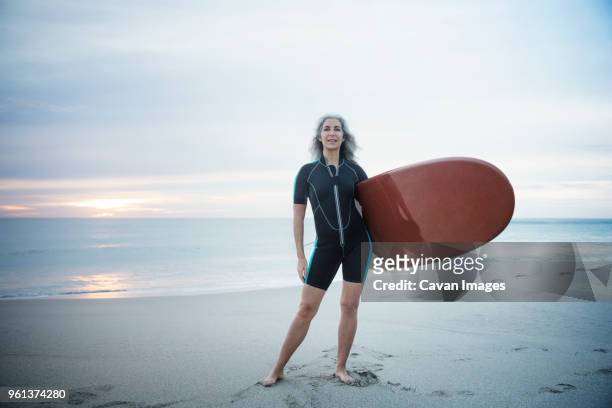 full length portrait of confident female surfer carrying surfboard at delray beach - beach hold surfboard stock-fotos und bilder
