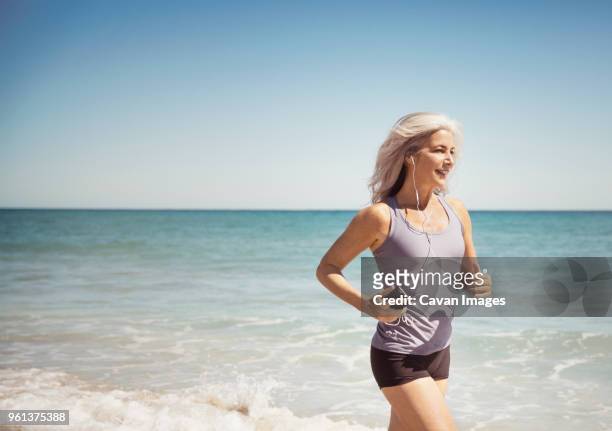 full length of fit woman running on sea shore at delray beach - one woman only shorts 50s stock pictures, royalty-free photos & images