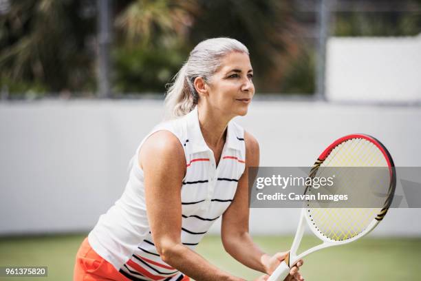 determined mature woman playing tennis on court - women tennis stock pictures, royalty-free photos & images