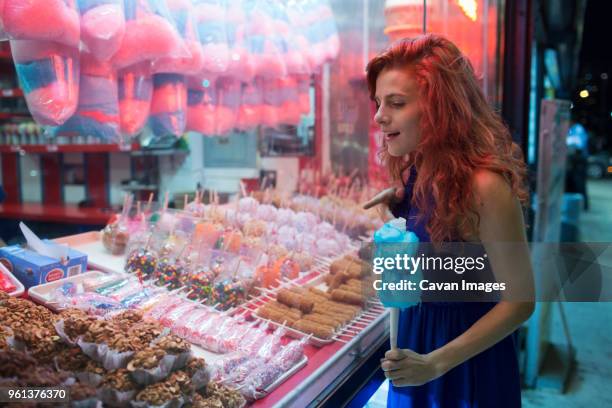 curious woman looking at deserts in stall at amusement park - new york food stockfoto's en -beelden