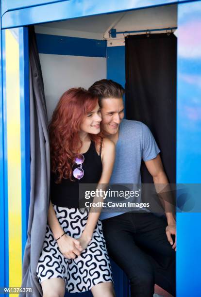 young couple sitting in photo booth smiling - photo booth couple stock pictures, royalty-free photos & images