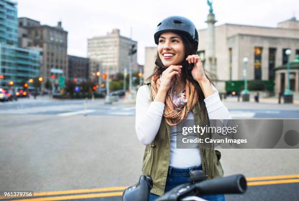 woman wearing helmet while standing with bicycle in city - cycling helmet stock pictures, royalty-free photos & images