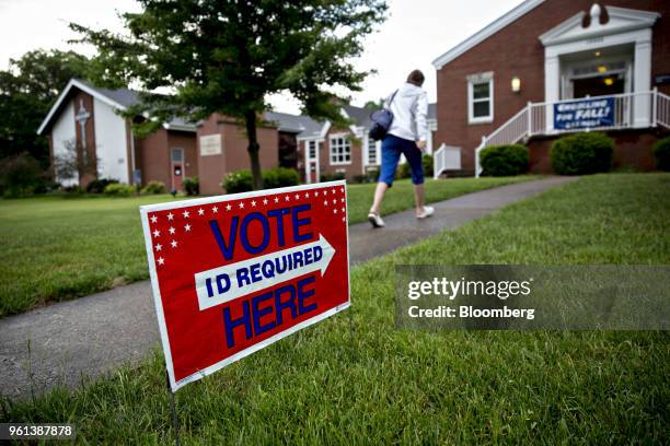 Pedestrian passes in front of a "Vote Here" sign outside a polling station in Louisville, Kentucky, U.S., on Tuesday, May 22, 2018. The fall election...