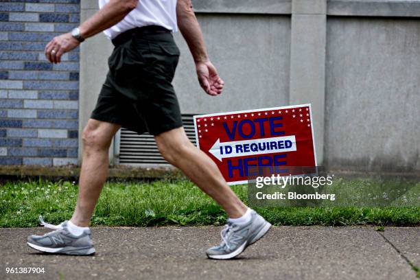 Pedestrian passes in front of a "Vote Here" sign outside a polling station in Louisville, Kentucky, U.S., on Tuesday, May 22, 2018. The fall election...