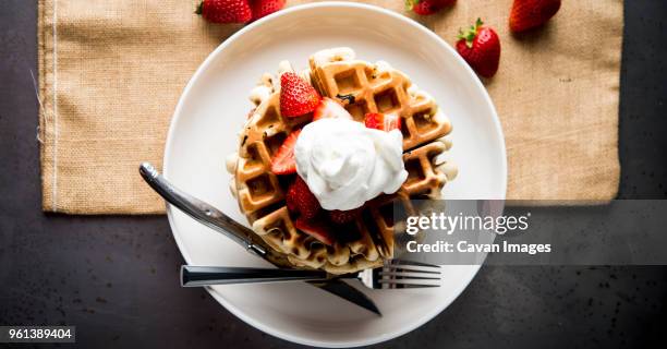 overhead view of waffles garnished with strawberries and whipped cream - strawberry and cream stock pictures, royalty-free photos & images
