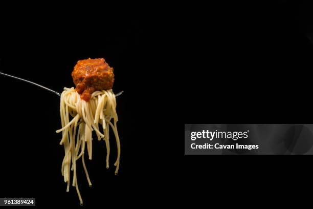 close-up of fork with spaghetti and meatball against black background - meatballs stock pictures, royalty-free photos & images