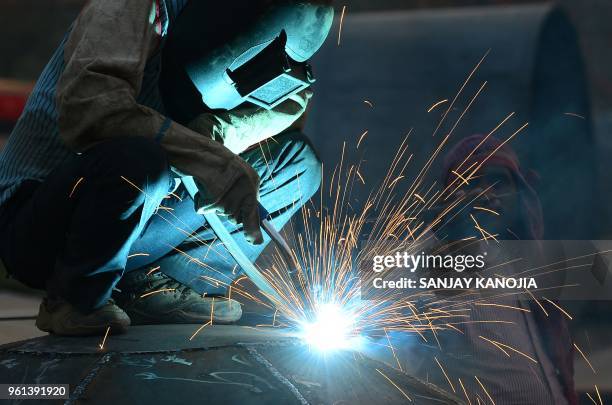 An Indian welder works on part of a pontoon at a workshop in Allahabad on May 22, 2018.