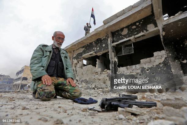 Member of the Syrian pro-government forces prays in a destroyed street in the Hajar al-Aswad neighbourhood on the southern outskirts of the capital...