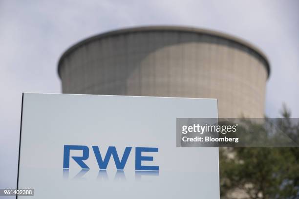 The RWE AG logo sits on a sign as a cooling tower stands at the company's gas powered power plant in Lingen, Germany, on Tuesday, May 22, 2018. RWE...