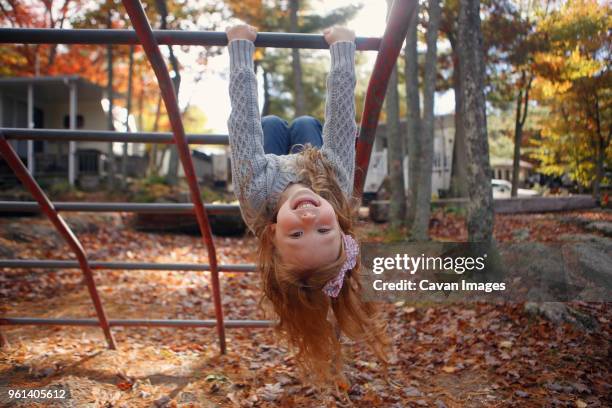 portrait of happy girl playing on jungle gym in playground during autumn - jungle gym stockfoto's en -beelden