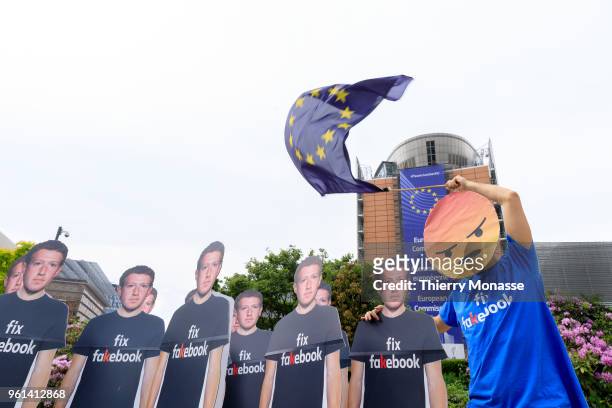 An Avaaz activist attends an anti-Facebook demonstration with cardboard cutouts of Facebook chief Mark Zuckerberg, on which is written "Fix...