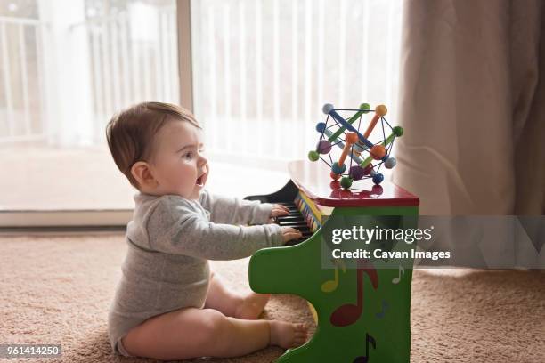 side view of curious baby boy playing toy piano at home - toddler musical instrument stock pictures, royalty-free photos & images