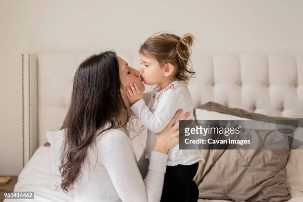 loving mother and daughter kissing on mouth at home - kissing mouth stock pictures, royalty-free photos & images