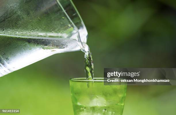 close up pouring purified fresh drink water from the bottle on table in living room - purified water stockfoto's en -beelden