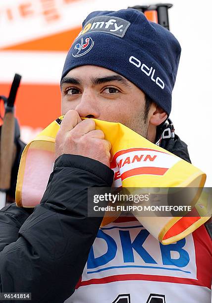 Simon Fourcade of France kisses the yellow jersey of the overall leader on the podium after the 12,5 km pursuit event of the Biathlon World Cup in...