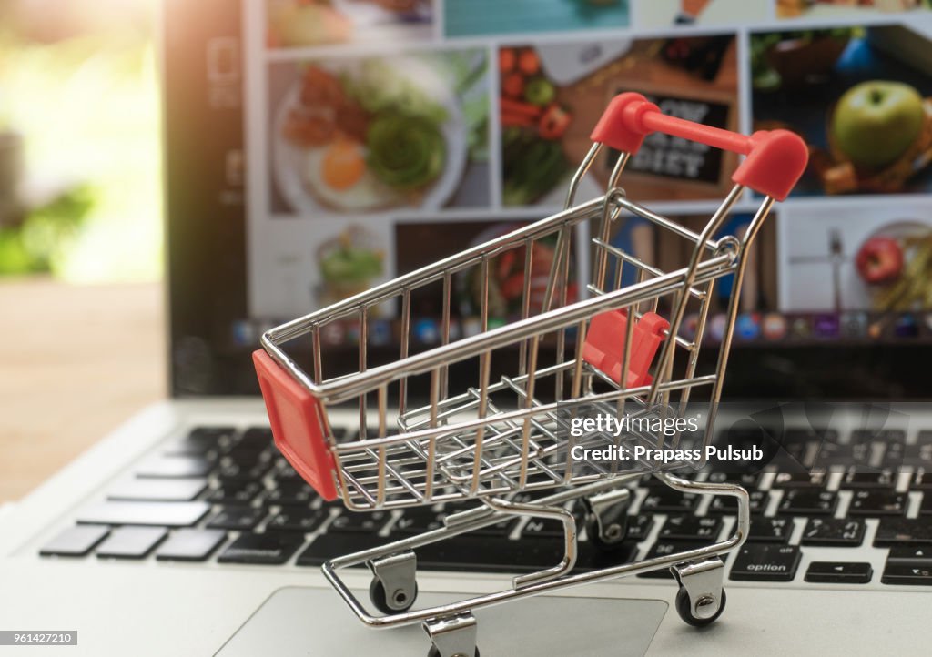 Online shopping and delivery service concept. in a shopping cart on a laptop keyboard, this image implies online shopping that customer order things from retailer sites via the internet.
