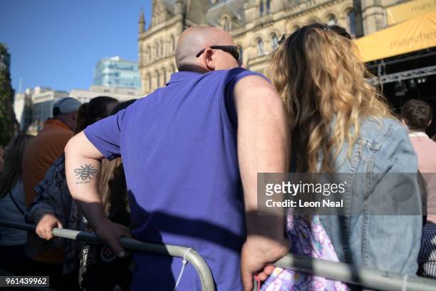 Man with a tattoo showing the date of last year's attack and the Manchester bee waits for an evening concert as tribute to the Manchester Arena...