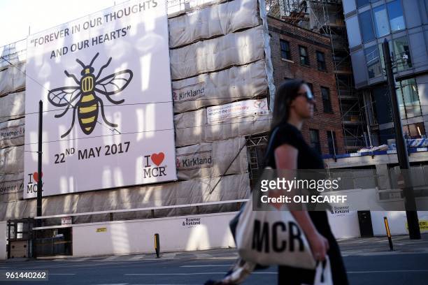 Woman carries an "I Love MCR" bag as she walks past a sign of support for Manchester, set up in the wake of the Manchester Arena bombing, in central...