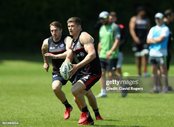 Owen Farrell runs with the ball with team mate Chris Wyles in support during the Saracens training session held at Old Albanians on May 22, 2018 in...