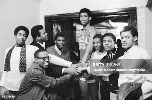 Boxing great Muhammad Ali, back row, second from left, looks up and smiles at UCLA basketball player Kareem Abdul Jabbar, back row, center, then...
