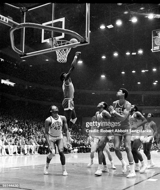 Center Lew Alcindor of the UCLA Bruins jockeys for the rebound as a teammate attempts to block a shot by a Loyola University player during a game in...