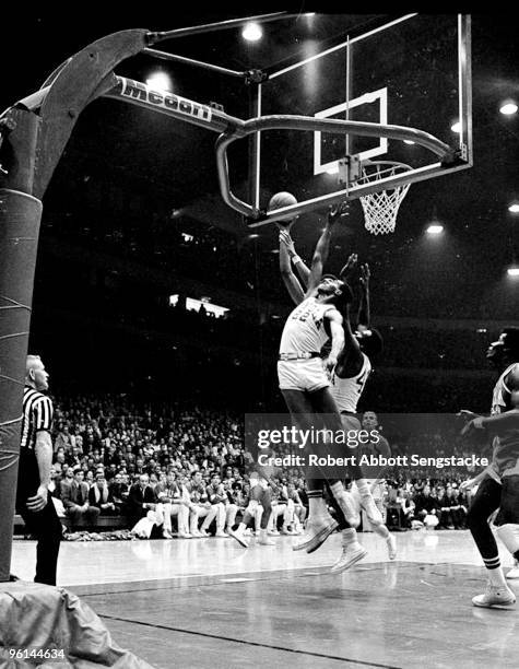 Bruins center Lew Alcindor, now known as Kareem Abdul Jabbar, is obscured behind two opposing players as he battles for the rebound in a game against...