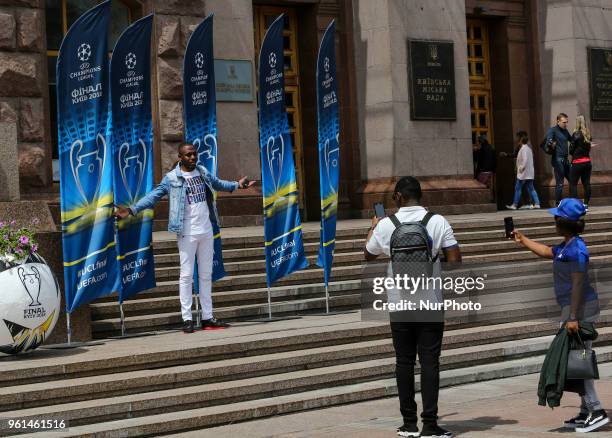 Woman poses for a picture in front of the flags with the UEFA Champions League final logo in central in Kyiv, Ukraine, May 22, 2018