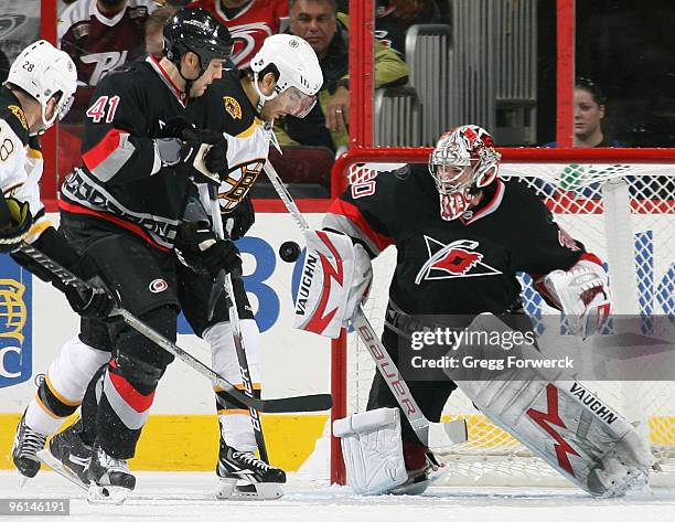 Cam Ward of the Carolina Hurricanes makes the save as teammate Andrew Alberts and Patrice Bergeron of the Boston Bruins create traffic during a NHL...