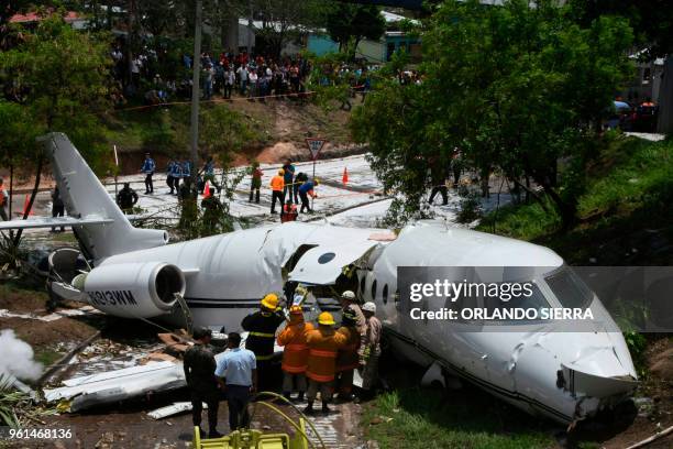 Emergency personnel, Honduran soldiers and police officers work at the site of an accident, after a plane went off the runway at Toncontin...