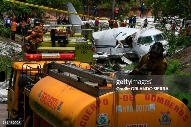 Firefighters and rescue personnel work at the site of an accident, after a plane went off the runway at Toncontin International airport and collapsed...