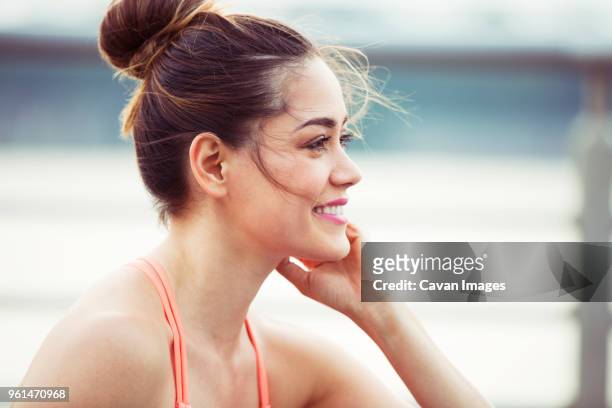 happy woman looking away while exercising - haarknoten stock-fotos und bilder