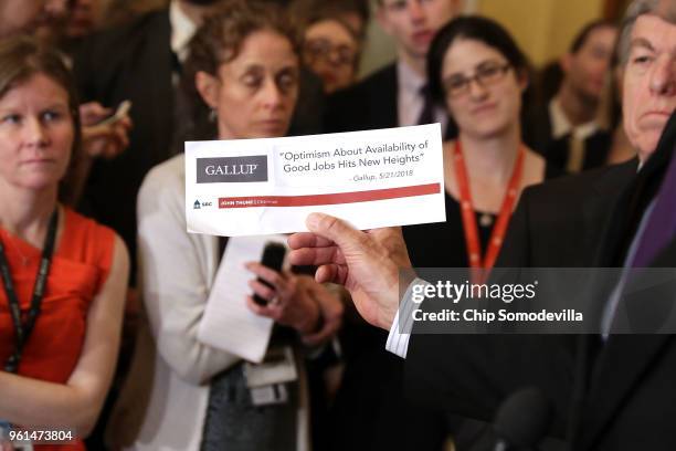 Sen. John Thune holds up Gallup headline while talking to reporters follow the weekly Senate Republican policy luncheon at the U.S. Capitol May 22,...