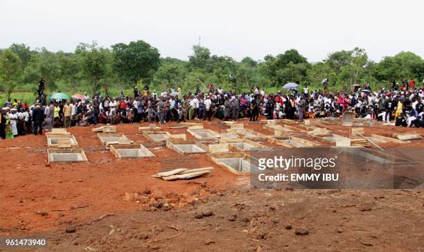 Graves of 17 worshippers and two priests, who were allegedly killed by Fulani herdsmen are watched by onlookers during a funeral service at...