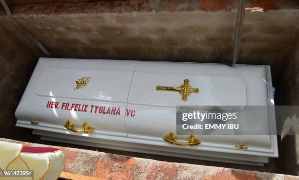 The coffin of Catholic priest Reverend Father Felix Tyolaha is lowered into a grave by unseen clergymen during a funeral service for 17 worshippers...