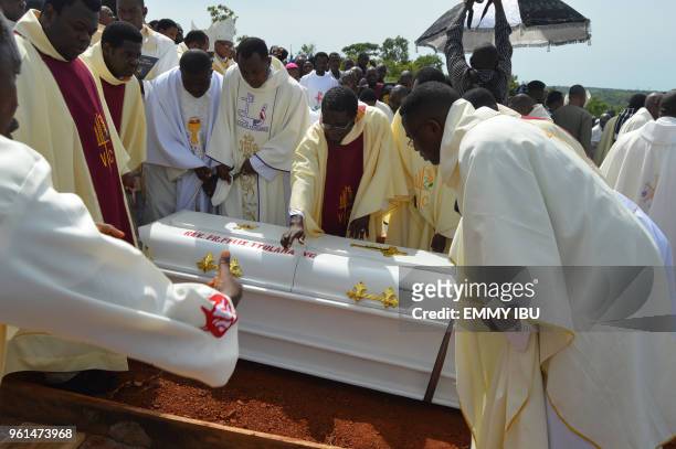 Clergymen prepare to lower a white coffin containing the body of a priest allegedly killed by Fulani herdsmen, into a grave for burial at...