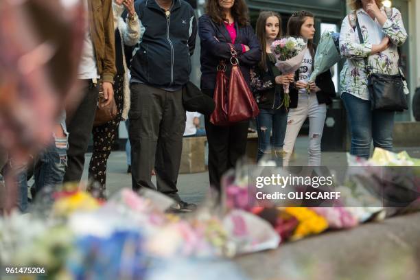 People pay their respects as they look at flowers and balloons left in central Manchester on May 22 the one year anniversary of the deadly attack at...