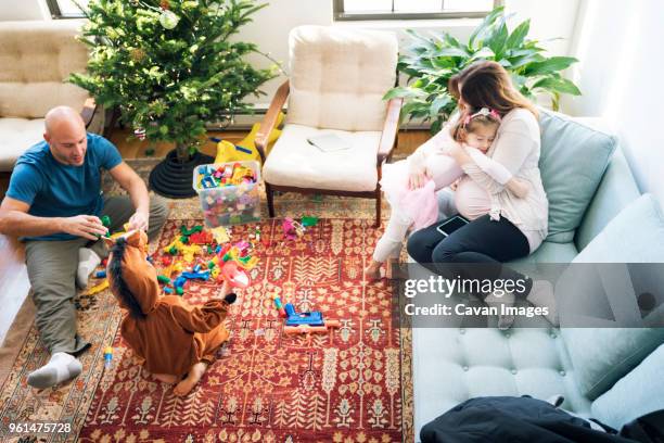 high angle view of father playing with son while girl embracing pregnant woman at home - 馬の衣装 ストックフォトと画像